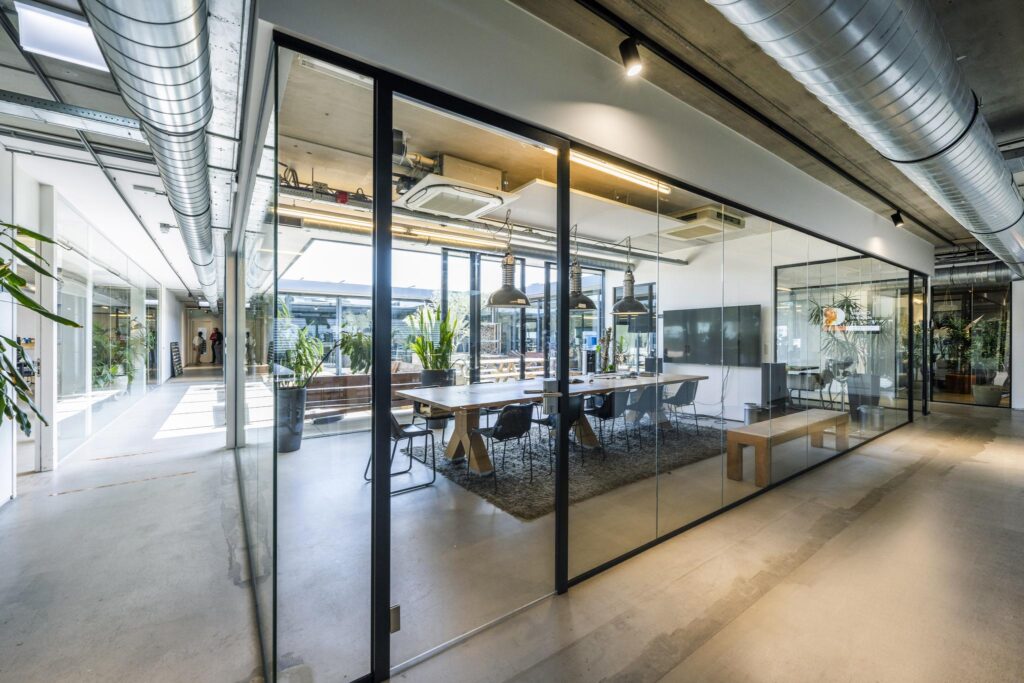 Modern glass-walled meeting room on Johan van Hasseltweg with industrial interior design and natural light.
